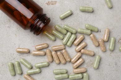 Pharmacist. Many different pills and overturned bottle on grey table, flat lay