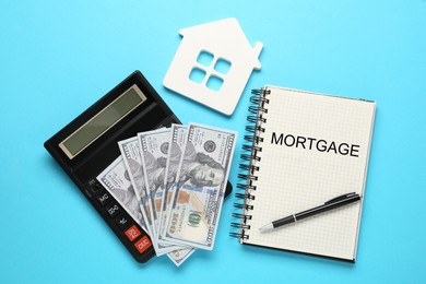 Image of Word Mortgage written in notebook, calculator and dollars on light blue background, flat lay