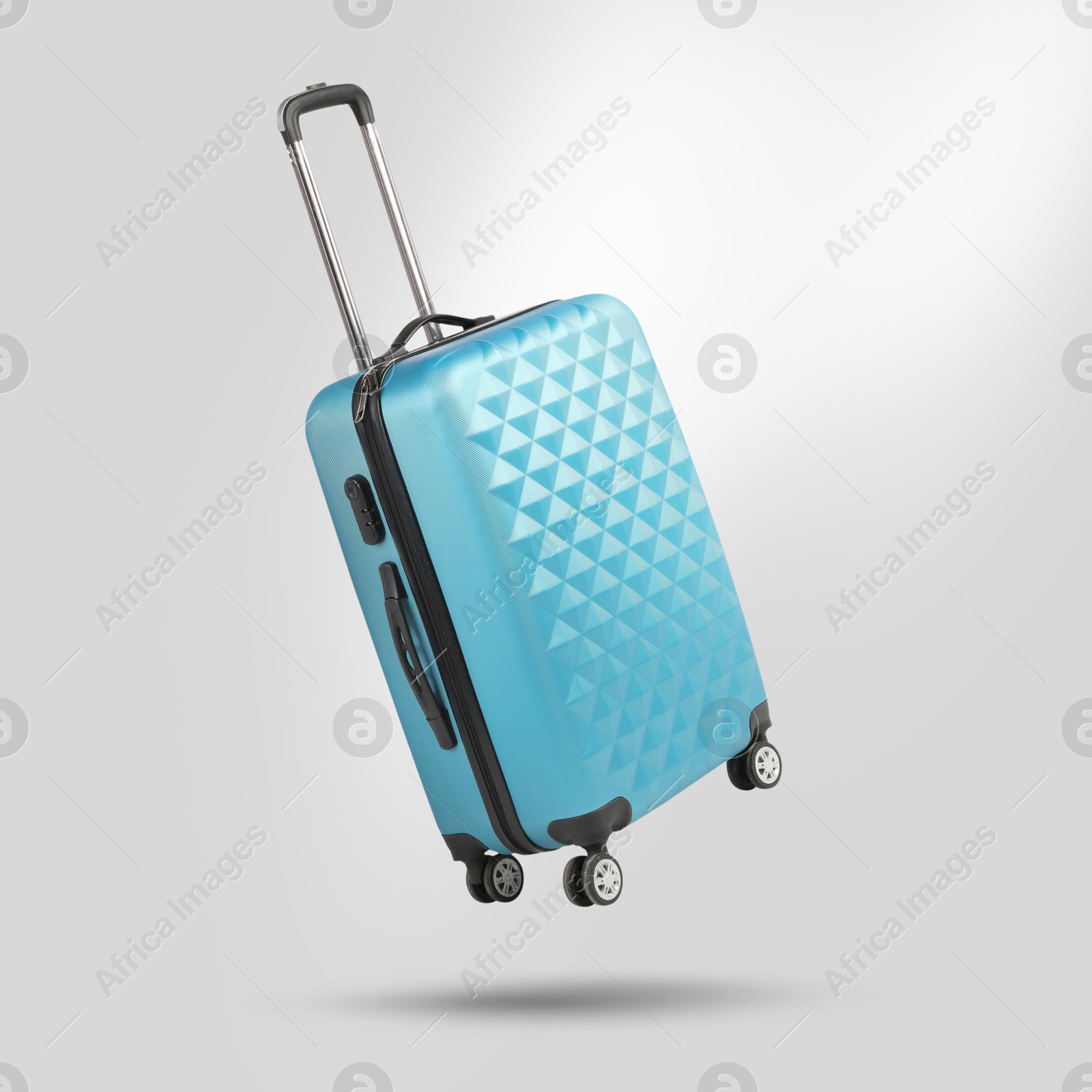 Image of Light blue suitcase in air on light grey background