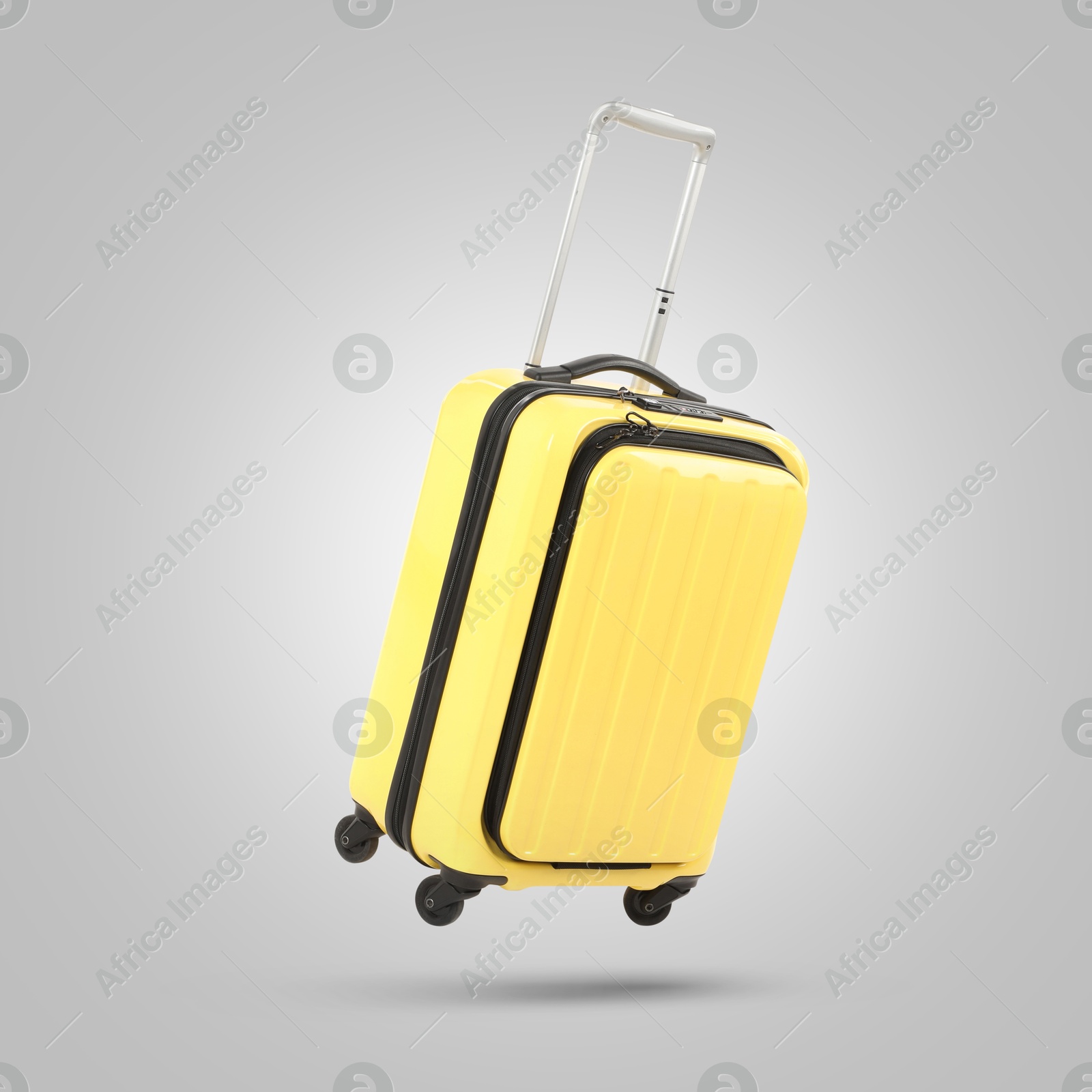 Image of Yellow suitcase in air on light grey background