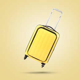 Yellow suitcase in air on yellow background