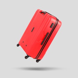 Red suitcase in air on light grey background