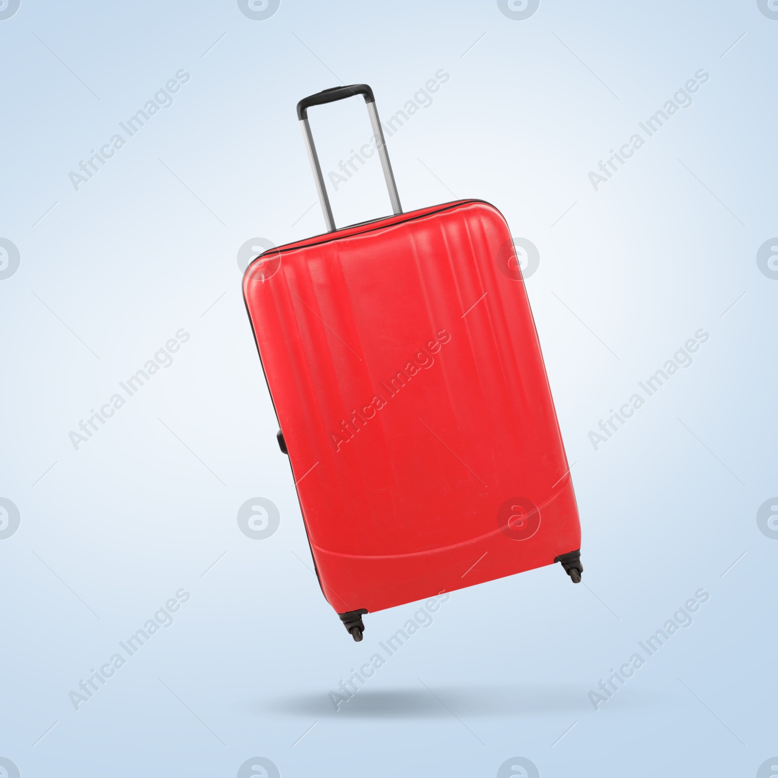 Image of Red suitcase in air on light blue background