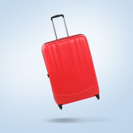 Red suitcase in air on light blue background