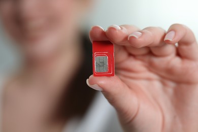 Photo of Woman holding SIM card indoors, closeup view