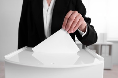 Woman putting her vote into ballot box indoors, closeup