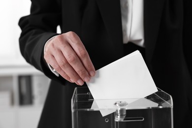 Woman putting her vote into ballot box indoors, closeup