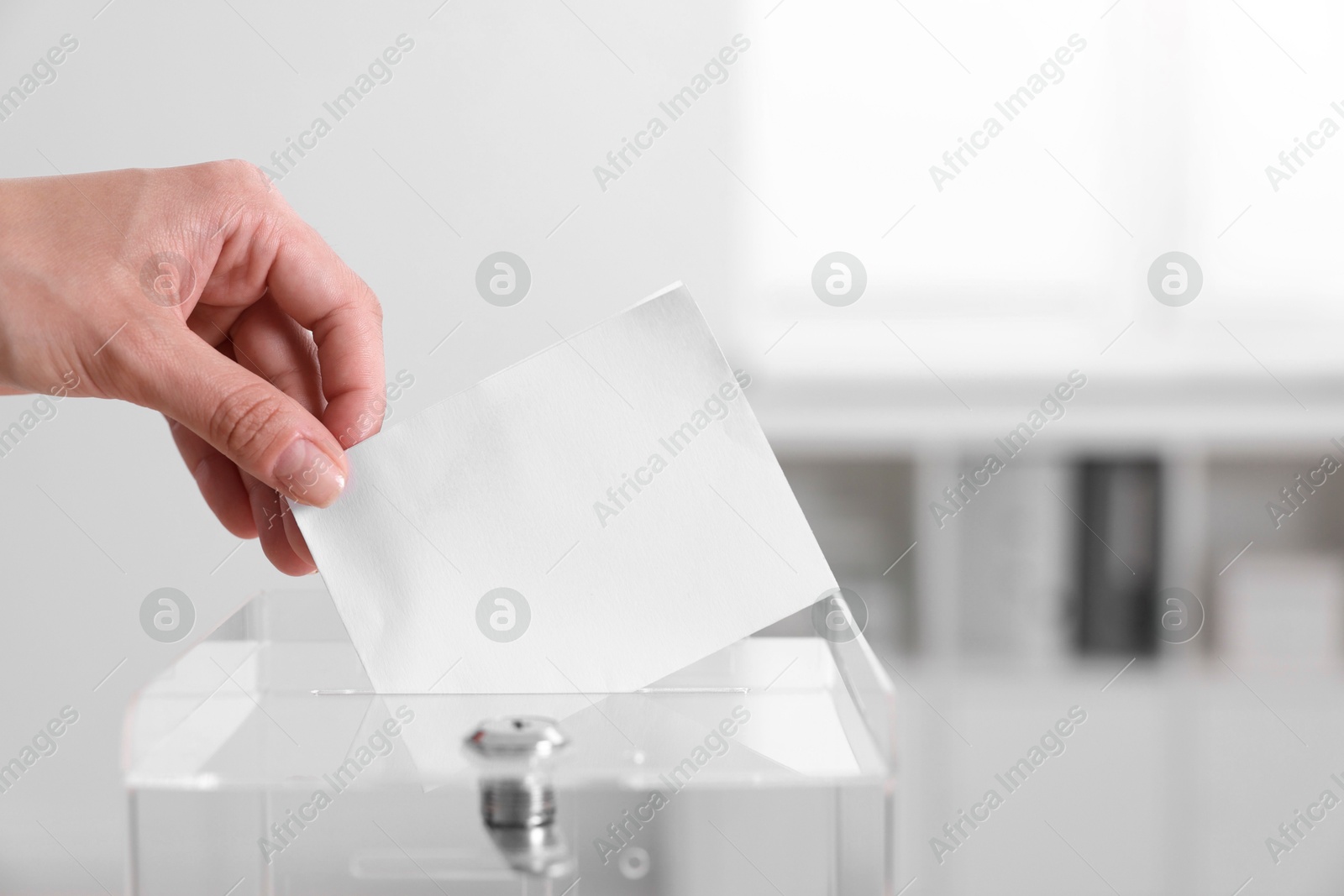 Photo of Woman putting her vote into ballot box indoors, closeup