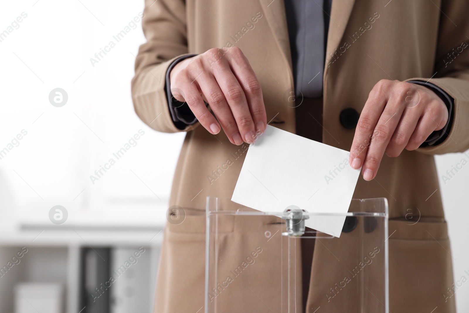 Photo of Woman putting her vote into ballot box indoors, closeup