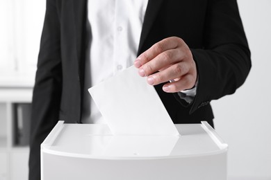 Man putting his vote into ballot box indoors, closeup