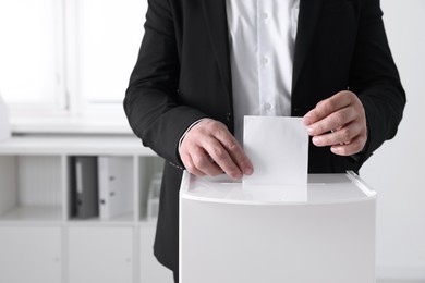 Man putting his vote into ballot box indoors, closeup