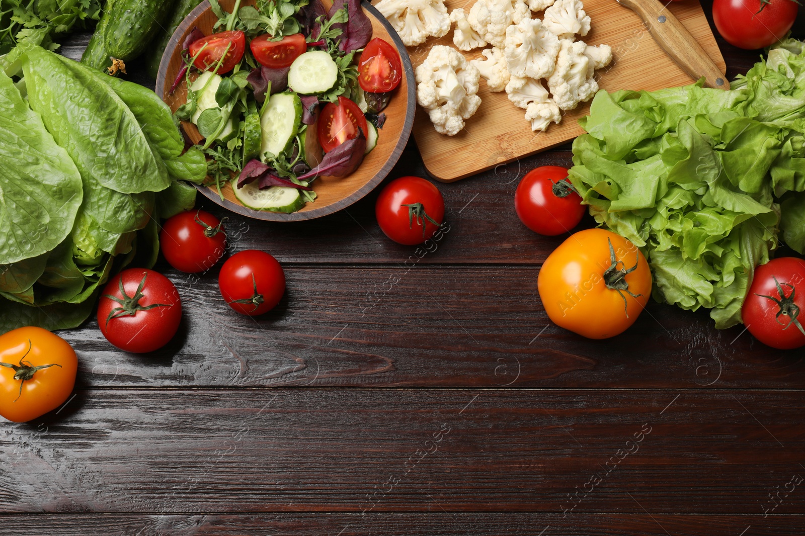 Photo of Healthy vegetarian food. Salad in bowl and vegetables on wooden table, flat lay. Space for text