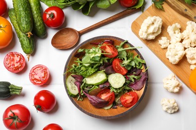 Photo of Healthy vegetarian food. Salad in bowl and vegetables on white tiled table, flat lay