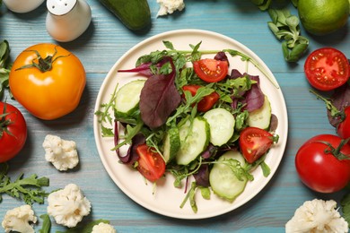 Healthy vegetarian food. Plate of salad and vegetables on light blue wooden table, flat lay