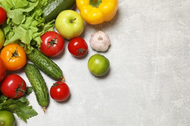 Photo of Healthy vegetarian food. Different vegetables and apples on grey textured table, flat lay. Space for text