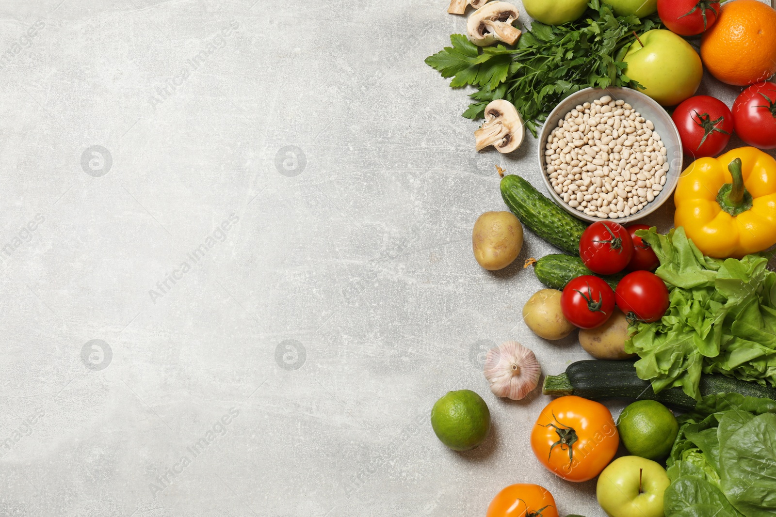 Photo of Healthy vegetarian food. Different vegetables, lentils, lime and apples on grey textured table, flat lay. Space for text