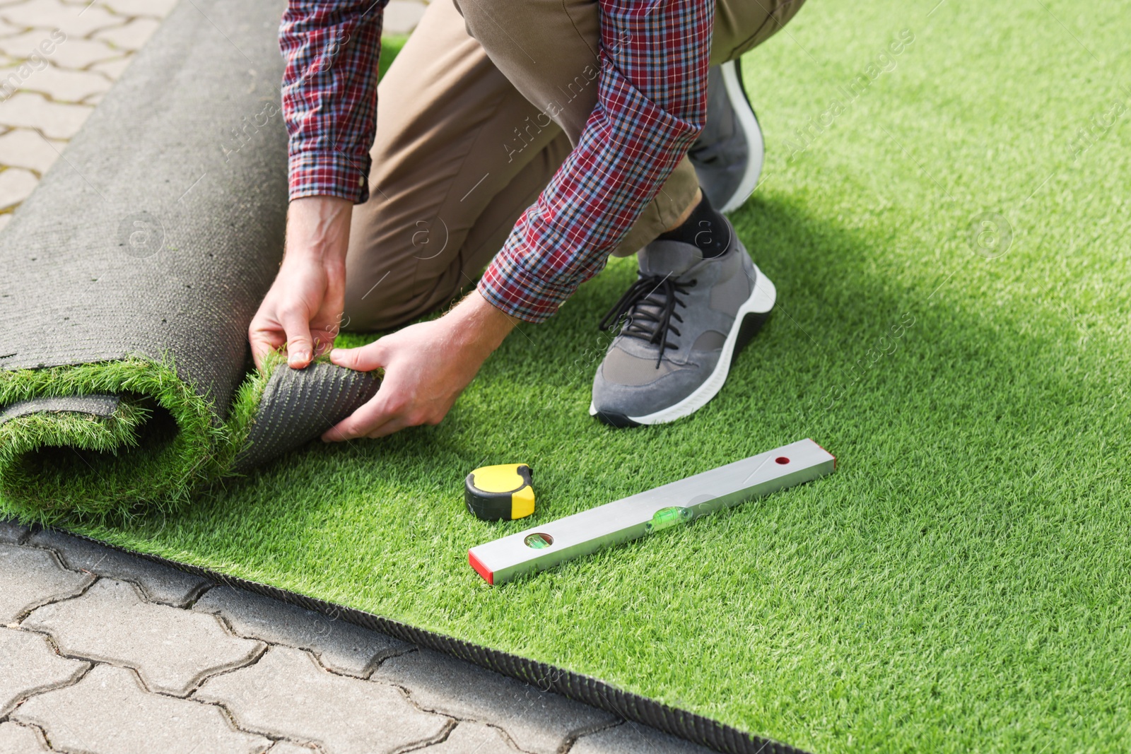 Photo of Man installing artificial turf outdoors, closeup view