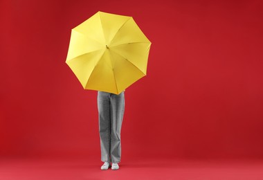 Photo of Woman with yellow umbrella on red background, space for text