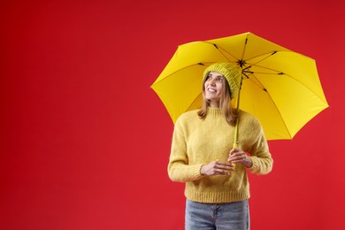 Woman with yellow umbrella on red background, space for text