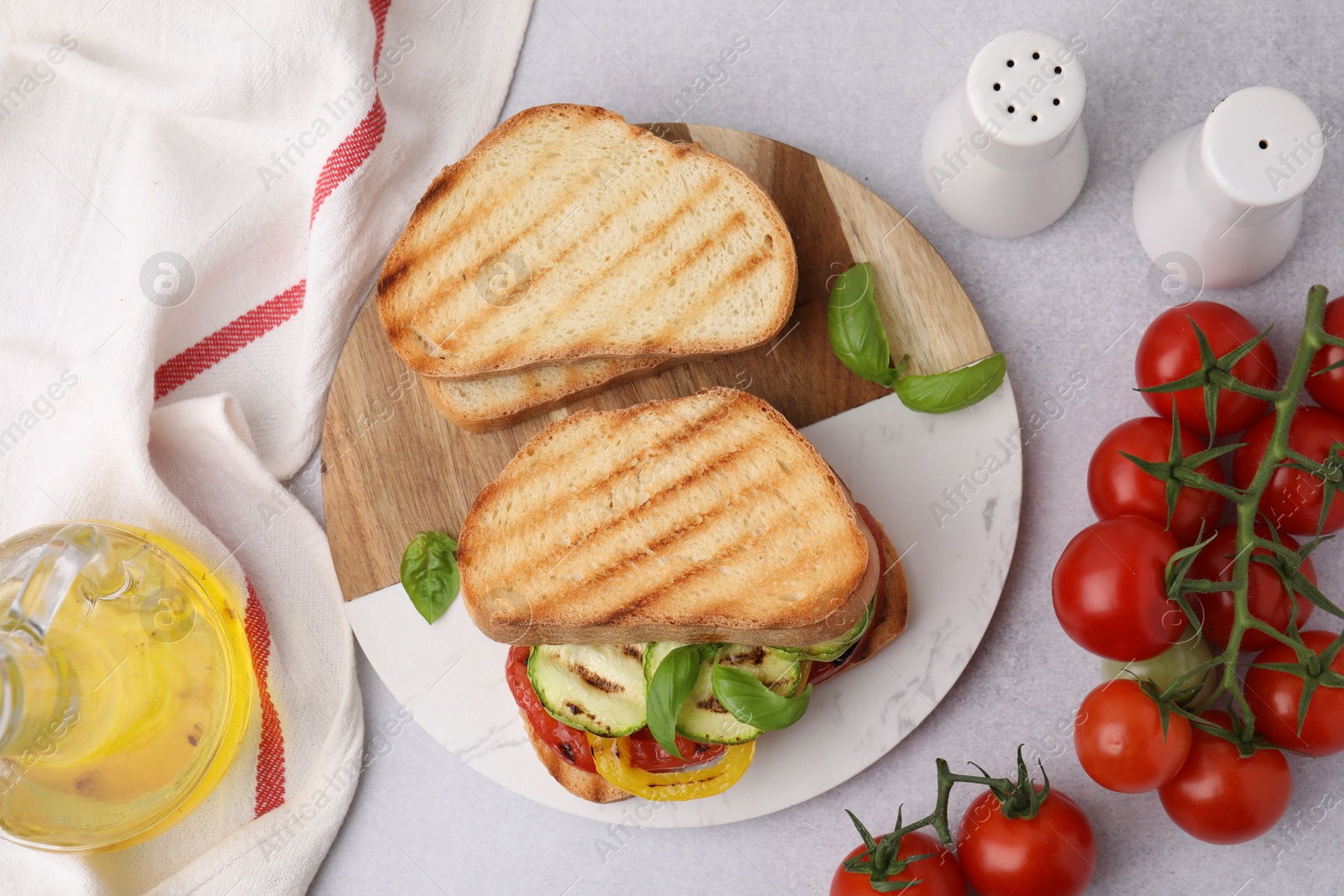 Photo of Tasty sandwiches with grilled vegetables, oil and spices on light table, flat lay