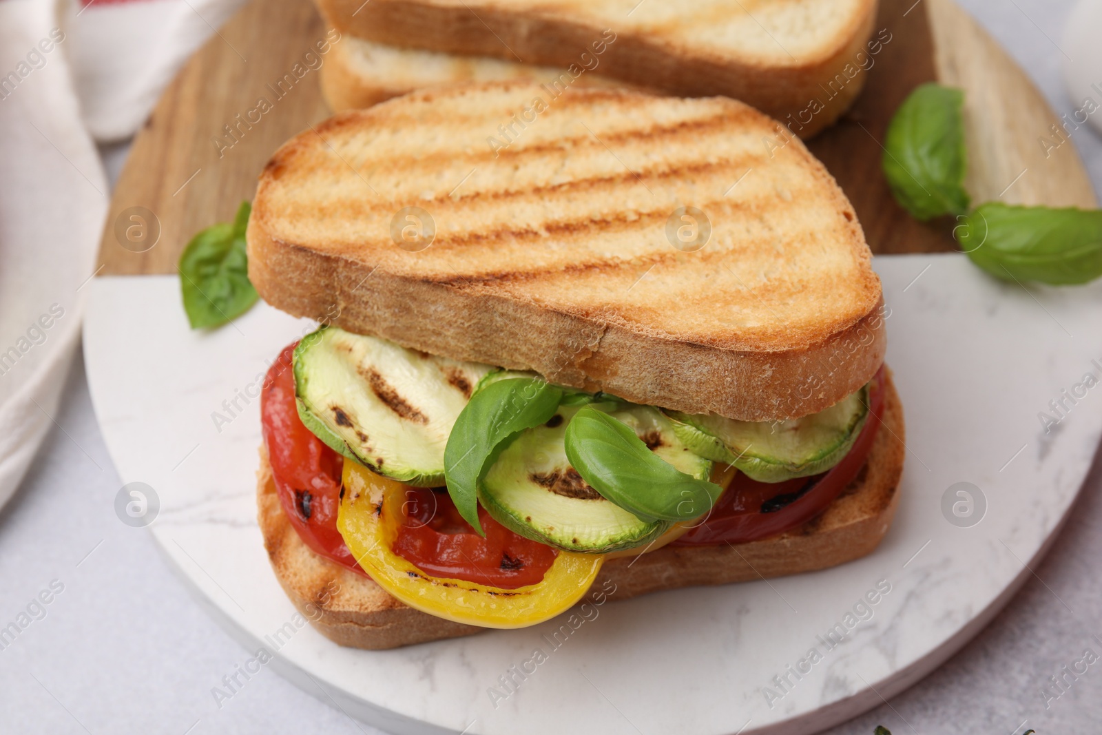 Photo of Tasty sandwich with grilled vegetables on light table, closeup