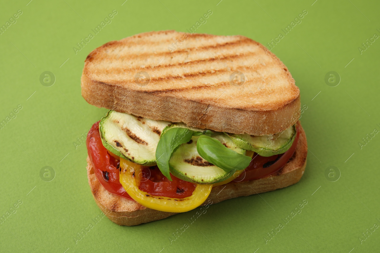 Photo of Tasty sandwich with grilled vegetables on green background, closeup