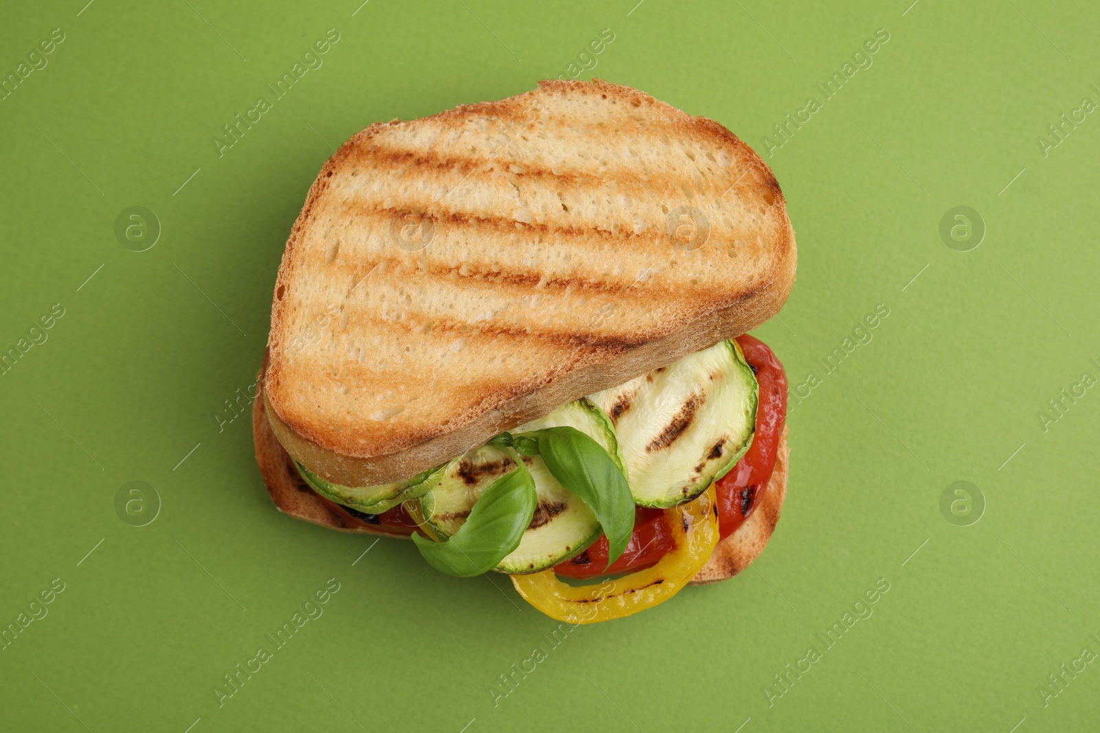 Photo of Tasty sandwich with grilled vegetables on green background, top view