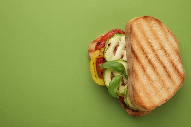 Photo of Tasty sandwich with grilled vegetables on green background, top view. Space for text