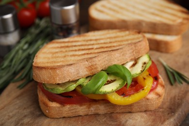 Photo of Tasty sandwich with grilled vegetables on wooden board, closeup