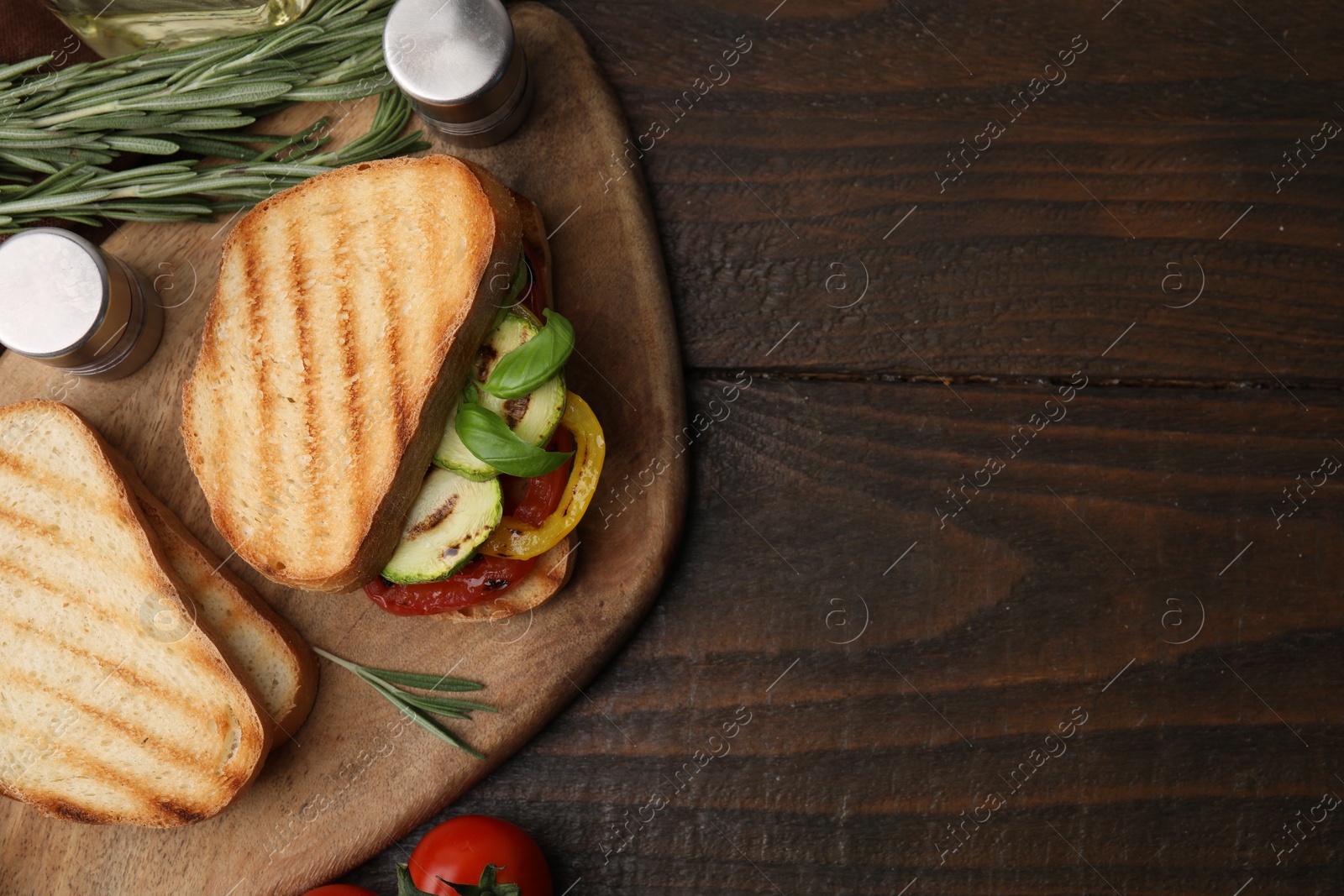 Photo of Tasty sandwich with grilled vegetables, rosemary and spices on wooden table, top view. Space for text