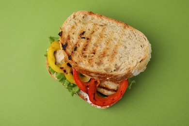 Photo of Tasty sandwich with grilled vegetables and cream cheese on green background, top view