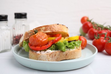 Photo of Tasty sandwich with grilled vegetables and cream cheese on white table, closeup