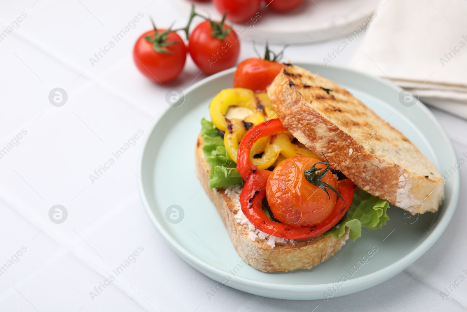 Photo of Tasty sandwich with grilled vegetables and cream cheese on white tiled table, closeup. Space for text