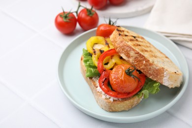 Photo of Tasty sandwich with grilled vegetables and cream cheese on white tiled table, closeup. Space for text