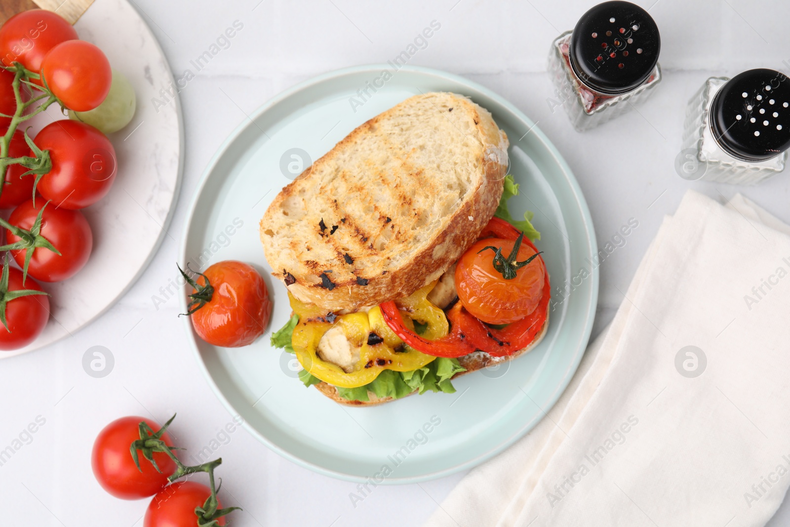 Photo of Tasty sandwich with grilled vegetables and spices on white tiled table, flat lay