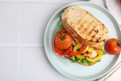 Tasty sandwich with grilled vegetables on white tiled table, top view. Space for text