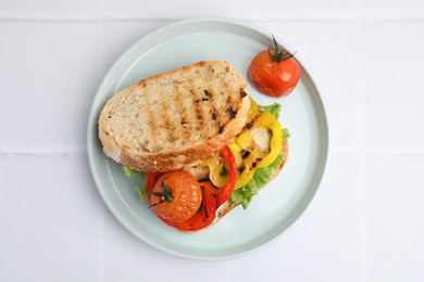 Tasty sandwich with grilled vegetables on white tiled table, top view