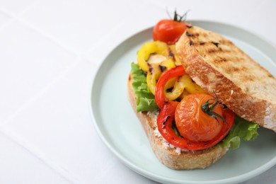 Tasty sandwich with grilled vegetables and cream cheese on white tiled table, closeup. Space for text