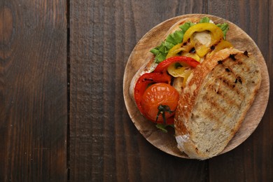 Photo of Tasty sandwich with grilled vegetables on wooden table, top view. Space for text