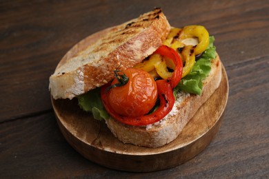 Photo of Tasty sandwich with grilled vegetables on wooden table, closeup