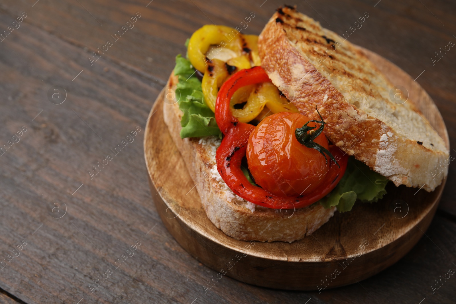 Photo of Tasty sandwich with grilled vegetables on wooden table, closeup. Space for text