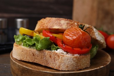 Tasty sandwich with grilled vegetables and cream cheese on wooden table, closeup