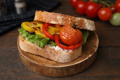 Photo of Tasty sandwich with grilled vegetables and cream cheese on wooden table, closeup