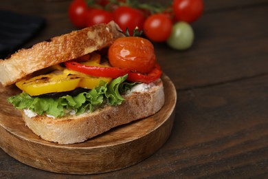 Tasty sandwich with grilled vegetables and cream cheese on wooden table, closeup. Space for text