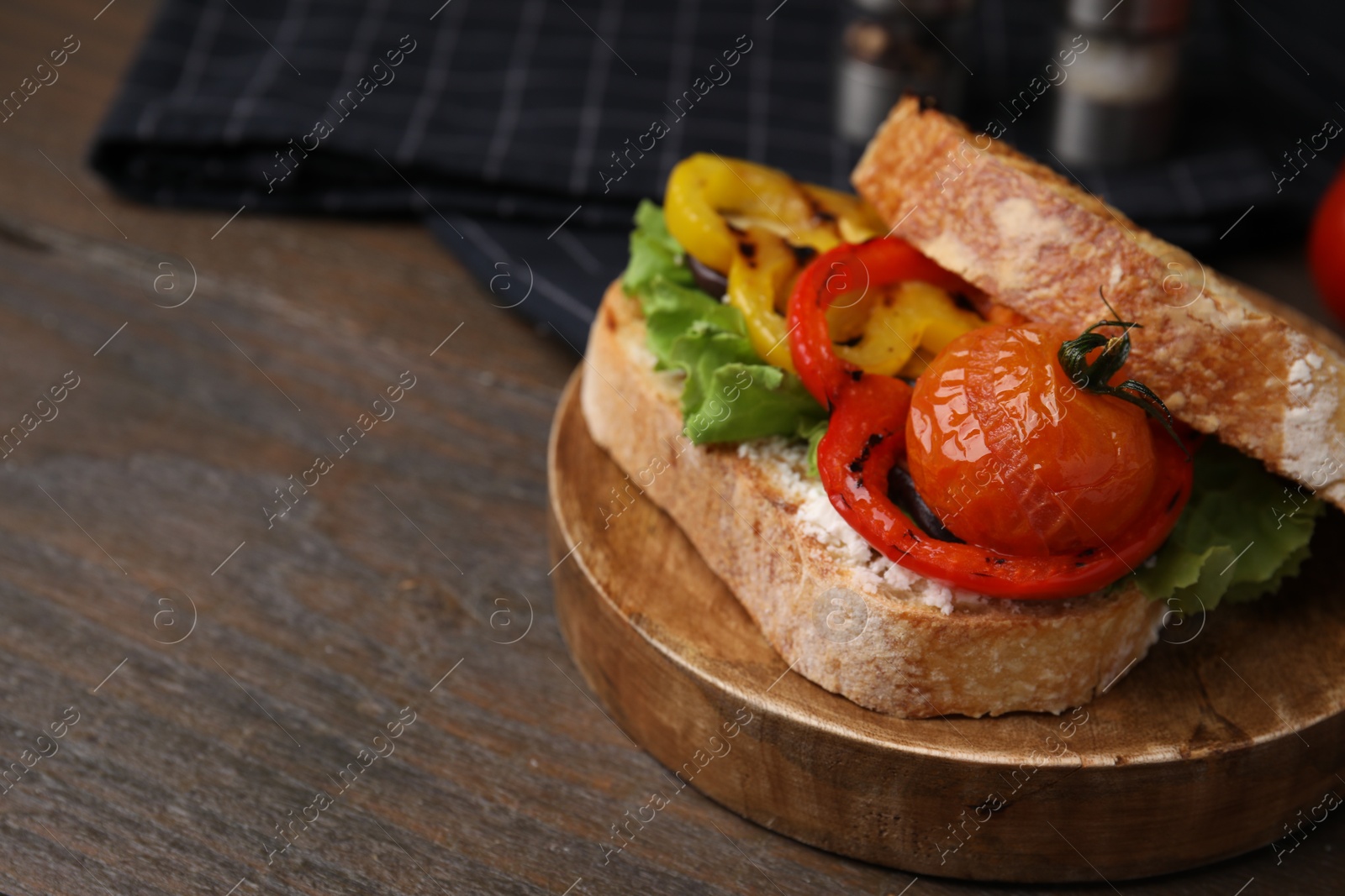 Photo of Tasty sandwich with grilled vegetables and cream cheese on wooden table, closeup. Space for text