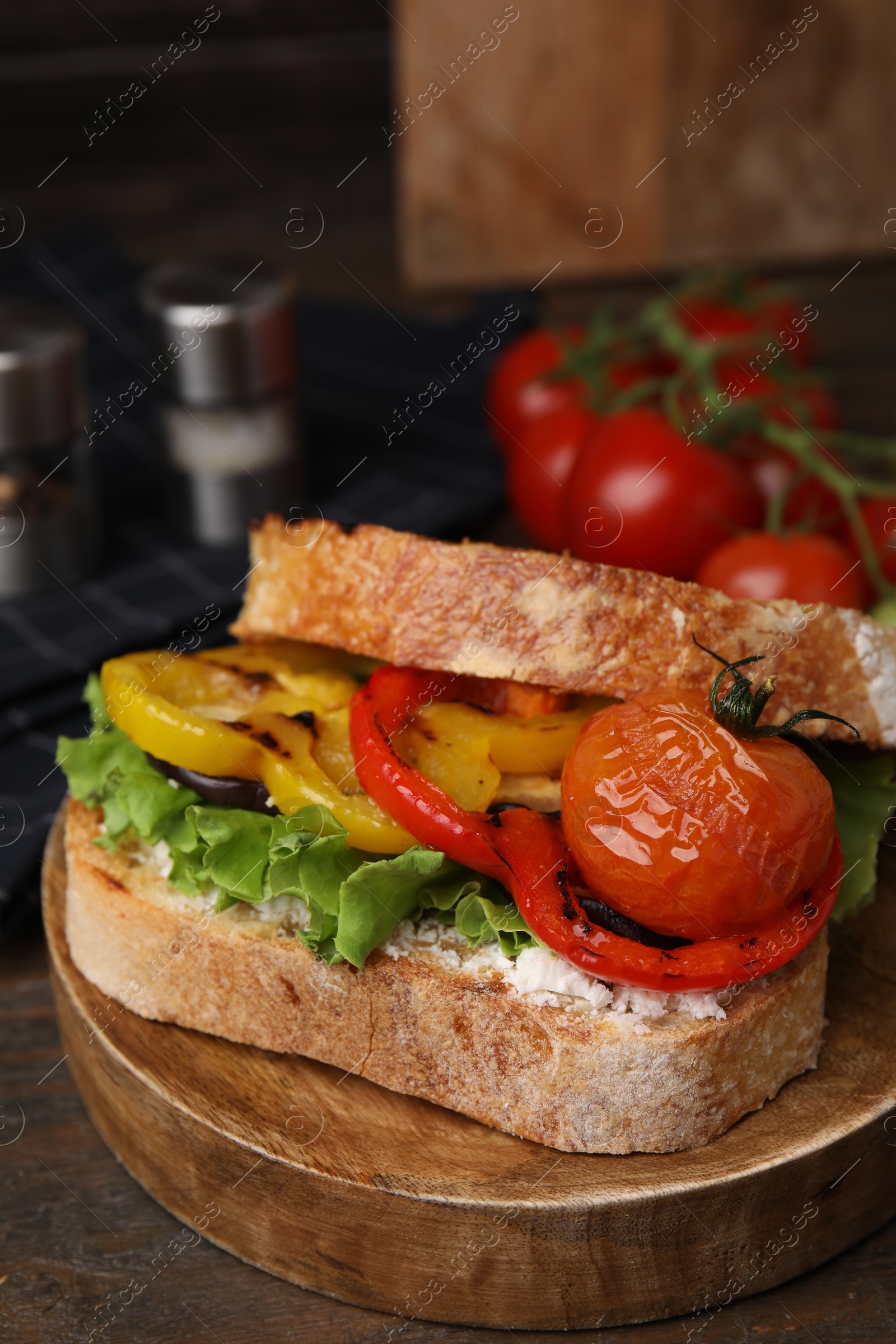 Photo of Tasty sandwich with grilled vegetables and cream cheese on wooden table, closeup