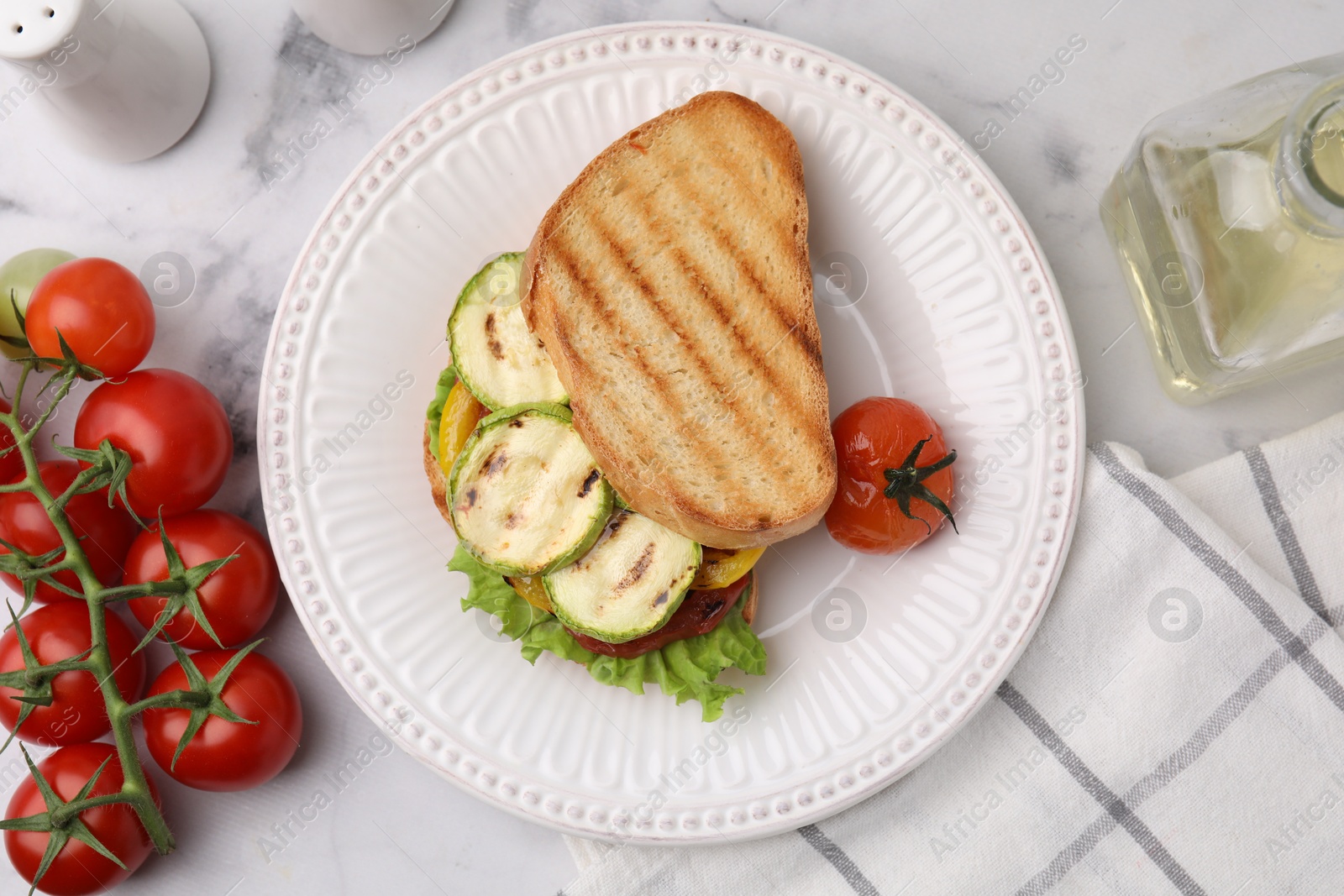 Photo of Tasty sandwich with grilled vegetables, fresh tomato and oil on white marble table, flat lay