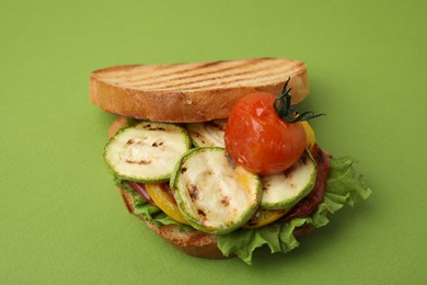 Photo of Tasty sandwich with grilled vegetables on green background, closeup