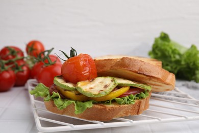 Photo of Tasty sandwich with grilled vegetables on white tiled table, closeup