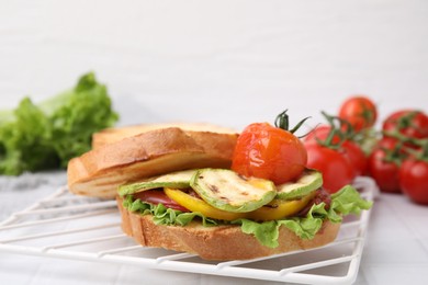 Photo of Tasty sandwich with grilled vegetables on white tiled table, closeup